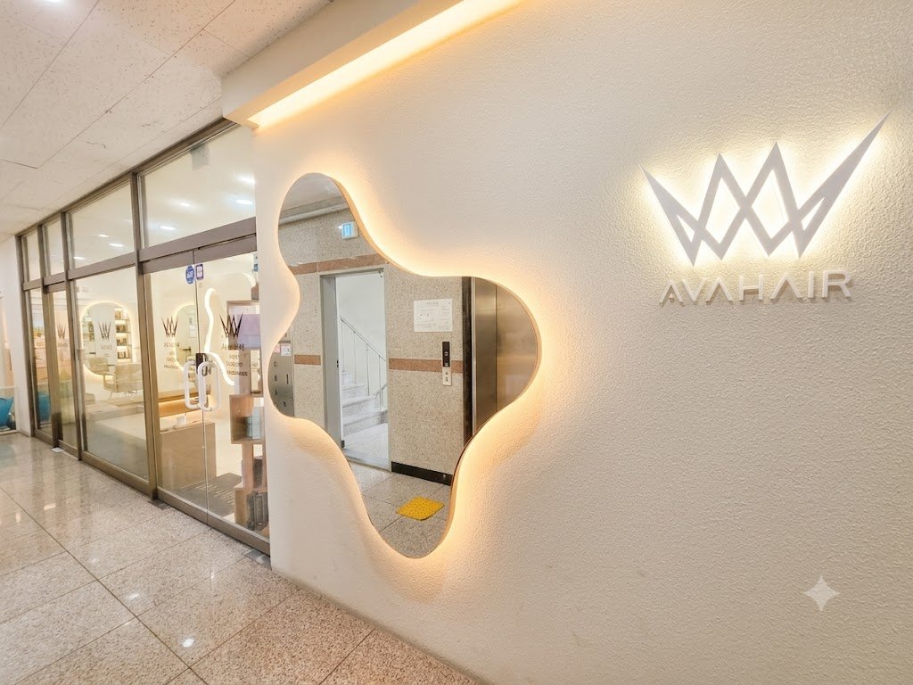 블롭 모양 거울과 AVAHAIR 로고 조명이 있는 매장 입구